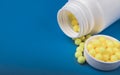 Yellow round vitamins white bottle on blue background Royalty Free Stock Photo
