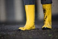Yellow rubber boots in a dirty puddle
