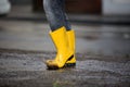 Yellow rubber boots in a dirty puddle