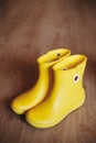 Yellow rubber boots isolated on wooden background Royalty Free Stock Photo