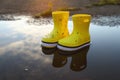 Yellow rubber boots in puddle outdoors, space for text. Autumn walk Royalty Free Stock Photo