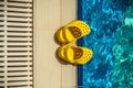 Yellow rubber children`s slippers on the edge of the pool as an abstract background. Rubber shoes are necessary near the pool for Royalty Free Stock Photo