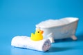 Yellow rubber duck for bathing with foam on a towel on a blue background with a bath Royalty Free Stock Photo