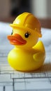 Yellow rubber duck with construction helmet on architectural blueprints, playful engineering concept Royalty Free Stock Photo