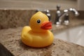 Yellow rubber duck water droplets on surface resting on a granite countertop Royalty Free Stock Photo