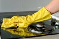 In a yellow rubber glove, a hand cleans a gas stove Royalty Free Stock Photo