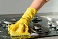 In a yellow rubber glove, a hand cleans a gas stove Royalty Free Stock Photo