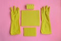 Yellow rubber gloves and different washcloths and cleaning rags on pink background. Cleaning or housekeeping concept background.