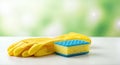 Bright yellow rubber gloves resting beside a blue and yellow sponge on a clean surface, showcasing essential cleaning tools for Royalty Free Stock Photo