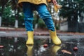 Yellow rubber shoes in puddle after raining. Falling leaves. Autumn season concept