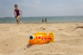 Yellow rubber toy fish on sand beach at the seaside and kids playing in the sea in background Royalty Free Stock Photo