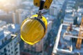 Yellow safety construction helmet on a crane hook, with a panoramic view of the site Royalty Free Stock Photo