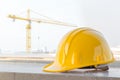 The yellow safety helmet at construction site with crane background Royalty Free Stock Photo