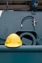 Yellow safety helmet on gunwale of fishing vessel with blurred background of green winch machine Royalty Free Stock Photo