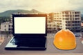 Yellow safety helmet and laptop on desk