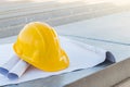 The yellow safety helmet put on the blueprint at construction site with crane background Royalty Free Stock Photo