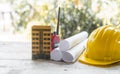 yellow safety helmet and rolled up architectural blueprints on a wooden desk Royalty Free Stock Photo