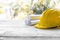 yellow safety helmet and rolled up architectural blueprints on a wooden desk Royalty Free Stock Photo