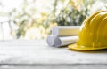 yellow safety helmet and rolled up architectural blueprints on a wooden desk Royalty Free Stock Photo