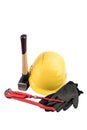 Yellow safety helmet with a sledgehammer with wooden handle, working gloves and adjustable plumbers wrench isolated on a white bac