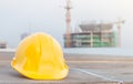 The yellow safety helmet on the table at construction site with crane background Royalty Free Stock Photo