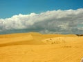 Yellow sand dunes under blue sky with white clouds Royalty Free Stock Photo