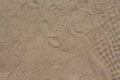 Yellow sand with foot marks photo texture. Shoe sole sand marks. Many tourist shoe protectors background