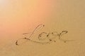 Yellow sand on Mediterranean sea shore with foamy wave and written word `love`.