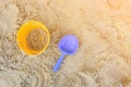 Yellow sand pail and blue shovel at the beach