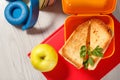 Yellow sandwich box with toasted slices of bread, cheese and green parsley, green apple, headphones and hardback books on Royalty Free Stock Photo