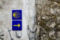 Yellow scallop shell and arrow on a wall signing the way to santiago de compostela in Galicia Royalty Free Stock Photo
