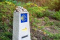 Yellow scallop shell, touristic symbol of the Camino de Santiago showing direction on Camino Norte in Spain.Column with rocks Royalty Free Stock Photo