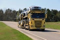 Yellow Scania Car Carrier Transports New Cars on Spring Road