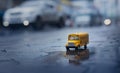 Yellow school bus toy model during hard rain fall in city.