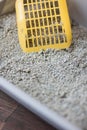 Yellow scoop standing on the litter sand on the litterbox. Royalty Free Stock Photo