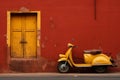 a yellow scooter parked in front of a red wall Royalty Free Stock Photo