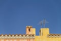 Yellow sea house roof with tiles, fireplace and television antenna in contrast with the blue Mediterranean sky Royalty Free Stock Photo