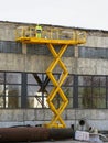 Yellow self propelled scissor lift in action with worker in uniform and safety protective equipment Royalty Free Stock Photo