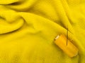 A yellow sewing thread spool lies on a textured yellow fabric Royalty Free Stock Photo