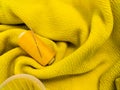 A yellow sewing thread spool lies on a textured yellow fabric Royalty Free Stock Photo