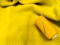 A yellow sewing thread spool lies on a textured yellow fabric Royalty Free Stock Photo