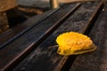 A yellow and shining fall leaf on a bank bench