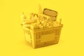 Yellow shopping basket with yellow food on yellow background. Food delivery