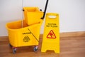 Yellow sign board with mop bucket on floor against wall Royalty Free Stock Photo