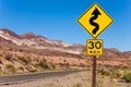 Yellow sign with curved arrow and road, California