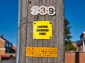 A yellow sign fixed to a wooden telegraph pole warns that optic fibre lines are overhead.