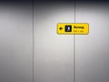 Yellow sign on grey wall with exit directions in three languages. Symbol of person leaving building. Exit sign with symbol of Royalty Free Stock Photo