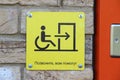 A yellow sign that reads in Russian `Call, you will be helped` and with a picture of a person in a wheelchair, arrows and doors. Royalty Free Stock Photo