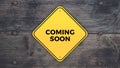 Yellow sign saying Coming Soon on a wooden background Royalty Free Stock Photo