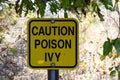 Yellow sign warning of dangers of poison ivy nearby Royalty Free Stock Photo